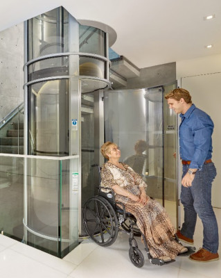 Man greeting woman in a wheelchair as she exits an elevator.